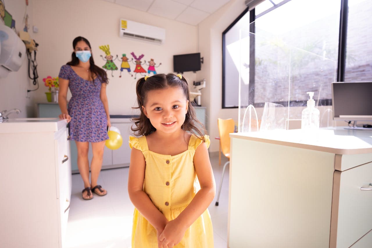 Smiling child in a yellow dress at a bright pediatric clinic